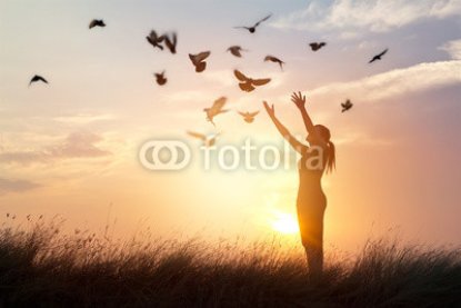 Woman-praying-and-free-birds-enjoying-nature-on-sunset-background.jpg