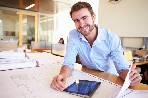 Male-Architect-With-Digital-Tablet-Studying-Plans-In-Office.jpg